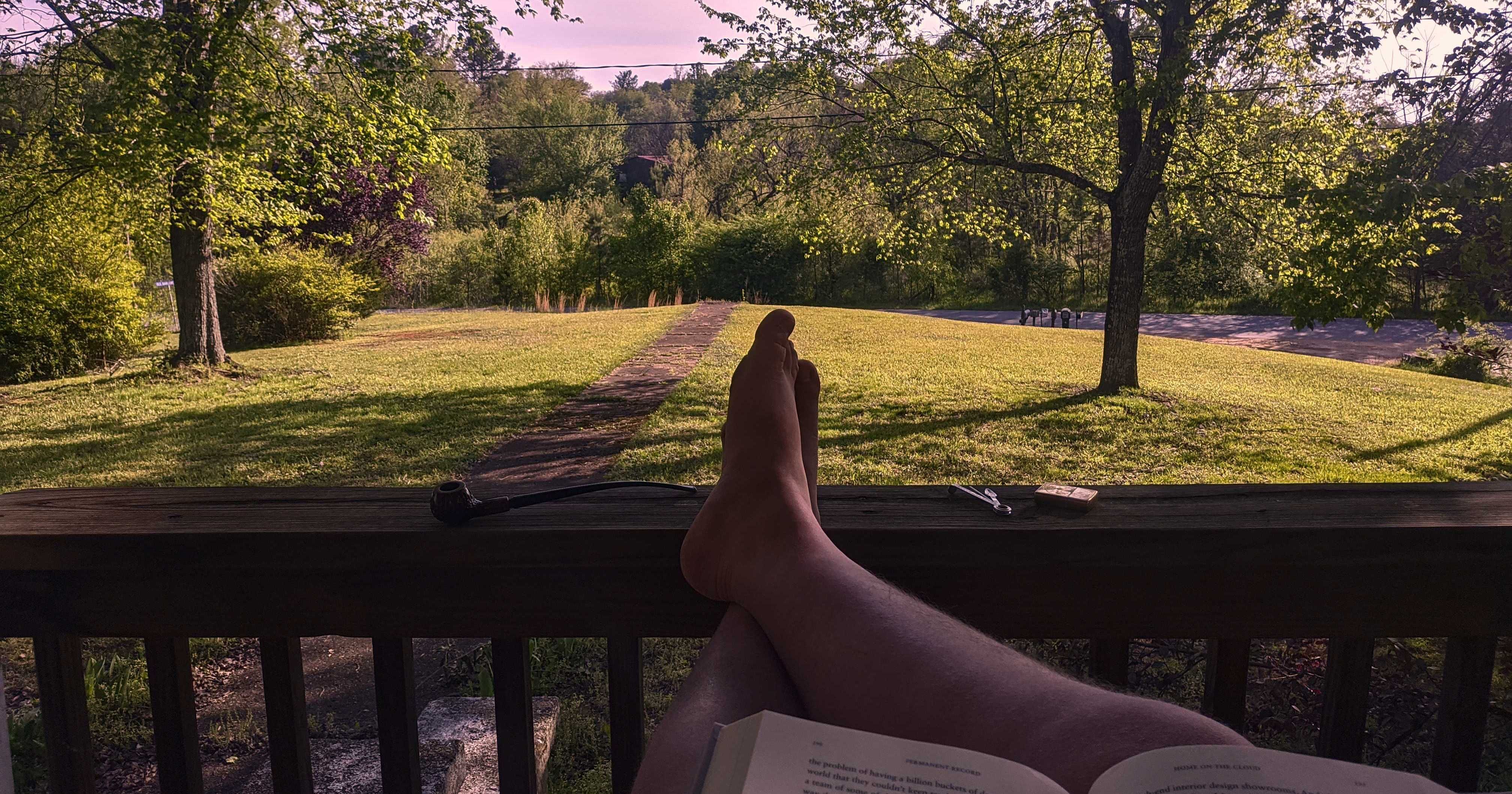 In this picture, you can see the top edge of the book I’m reading, my
crossed legs resting on the porch rail, my churchwarden to the left, and
my light and pipe tool to the right. This is the same “warm” scene as
described in the picture of Armellini’s pipe; it’s very
peaceful